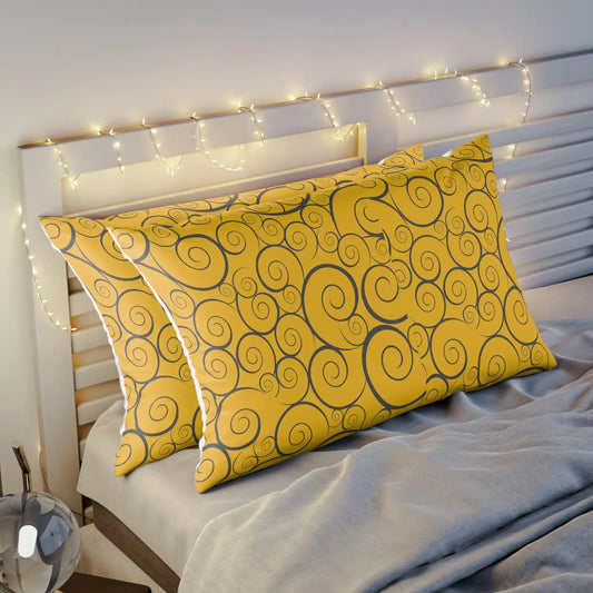 Two yellow pillows with swirl patterns on a bed with fairy lights.