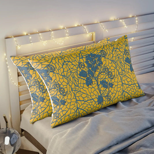 Two yellow floral patterned pillows on a bed with fairy lights.