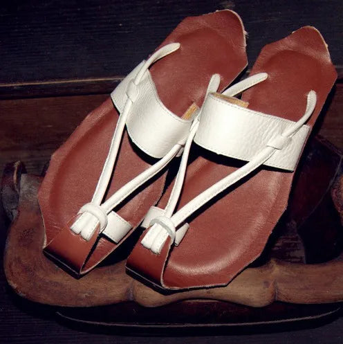 Brown and white sandals on a dark wooden background.