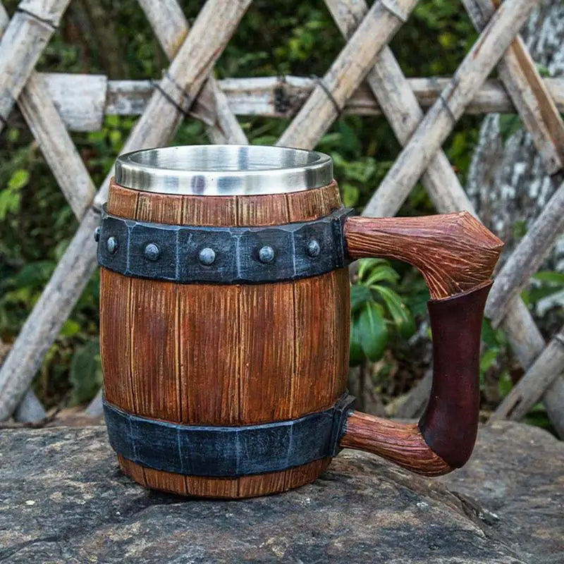 Wooden barrel-shaped mug with metal trim and curved handle outdoors.