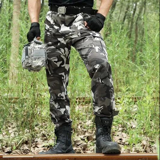 Person in camouflage pants and boots holding a silver case.